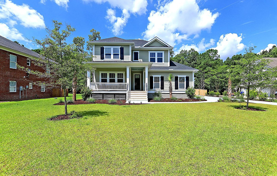 A classic two-story home built on a spacious homesite with wooded acreage visible in the background.