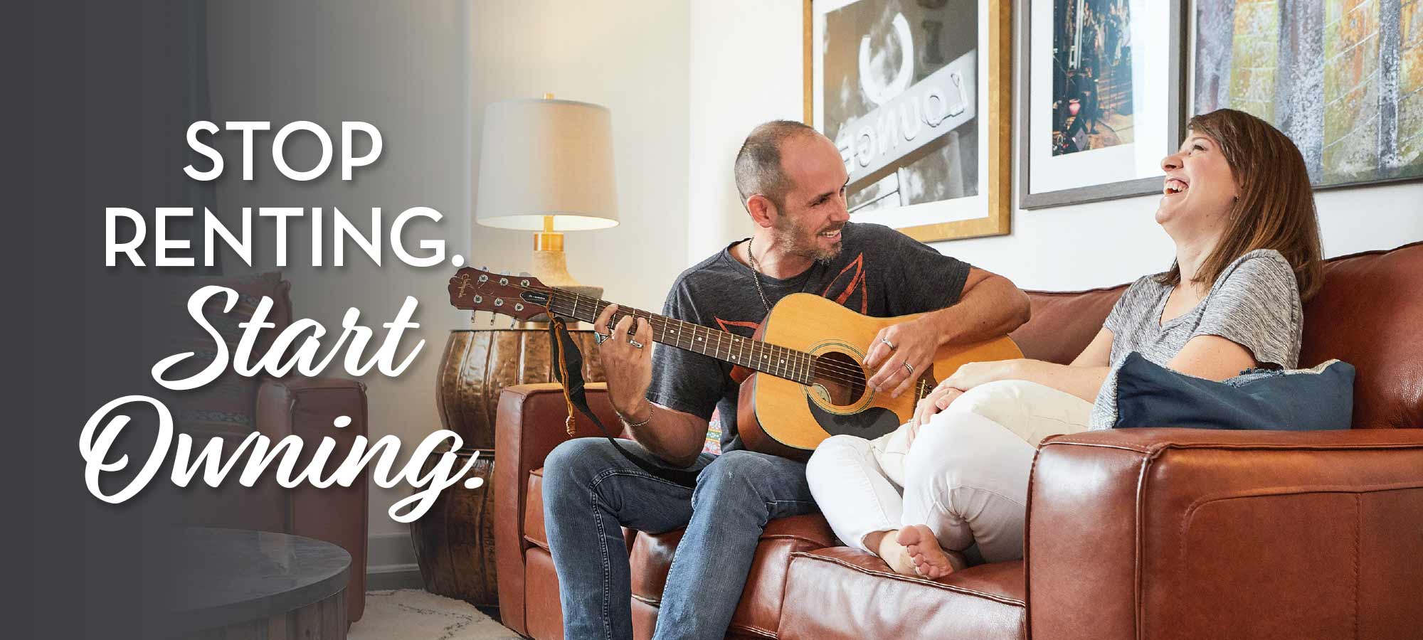 photo - man and women sitting on couch smiling, man is playing a guitar