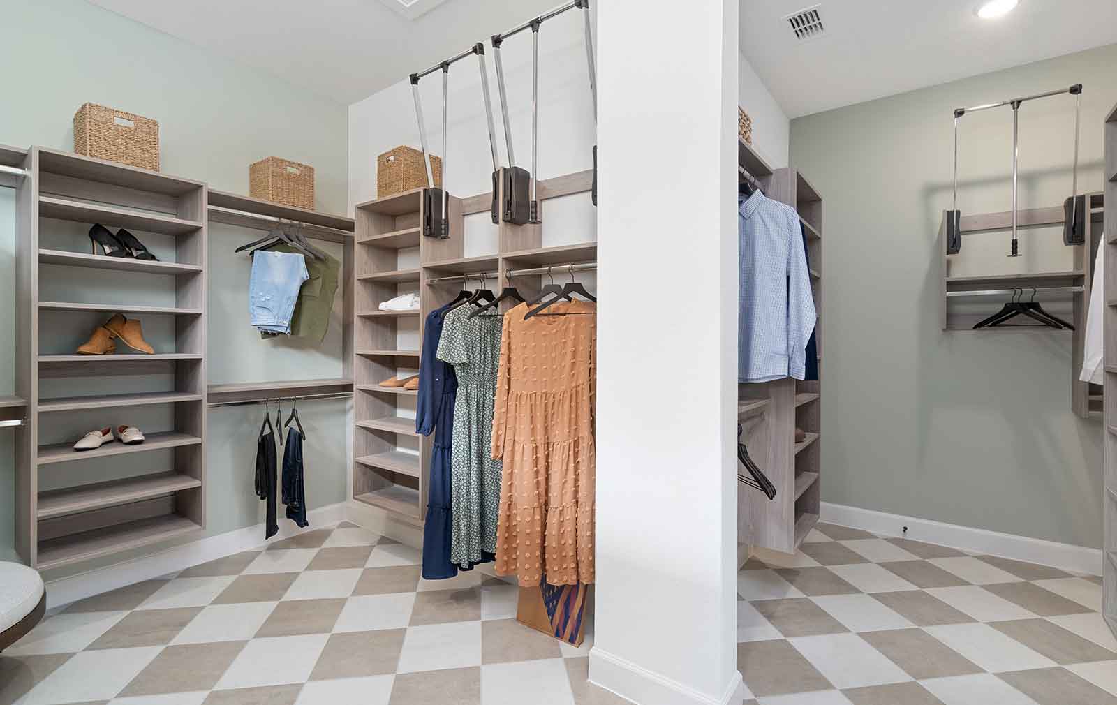 Light checkerboard tiles, off-brown shelving and green walls frame the interior of a walk-in closet, where a few pair of shoes, hanging garments and raffia baskets show off what each type of fixture can be used for without making the space appear stuffed or messy.