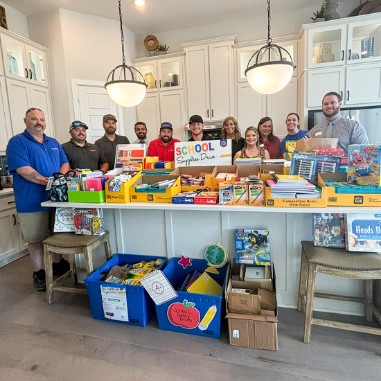 DWH Team Members from Dallas posing with a counter full of school supplies