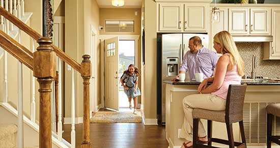 child coming thrhough front door while parents sit in kitchen